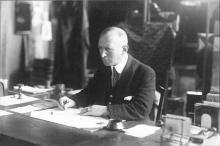 hoofd en lichaam naar links gedraaid, opkijkend, zittend achter een bureau