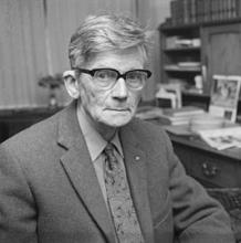 hoofd en lichaam naar rechts gedraaid, aankijkend, achtergond: bureau me boeken